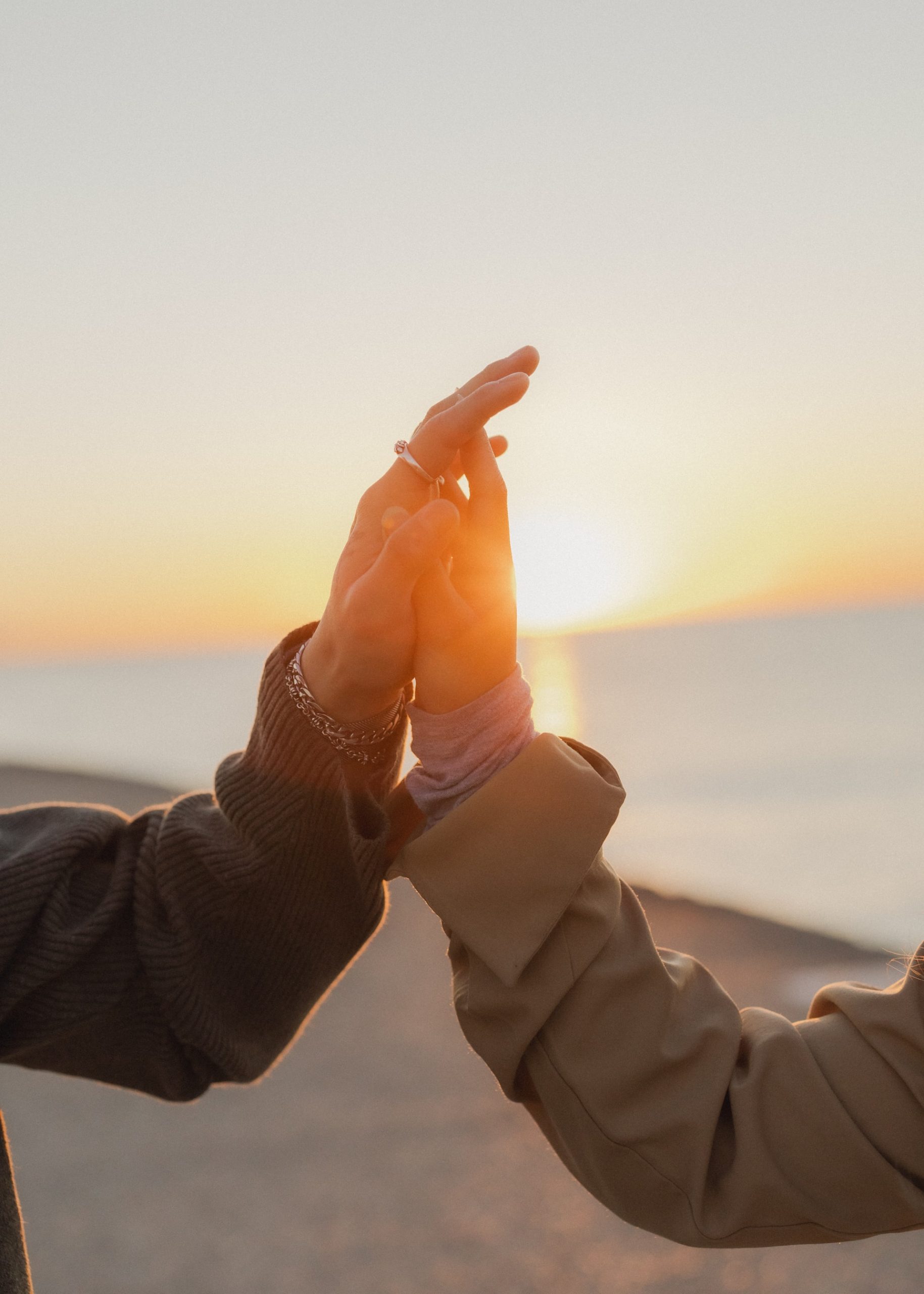 engagement session hands together in front of  sun