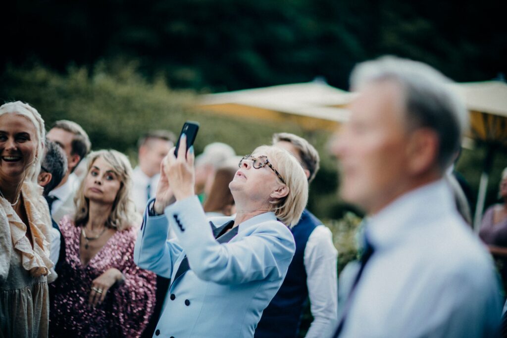 Older wedding guest capturing a candid moment on her phone